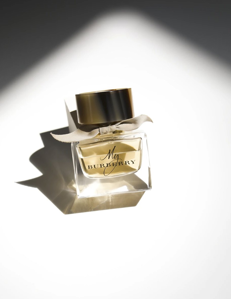 Goldener Parfumflakon mit hartem grafischem Schlagschatten auf Weiss — Das Studiozwei, Werbefotograf München