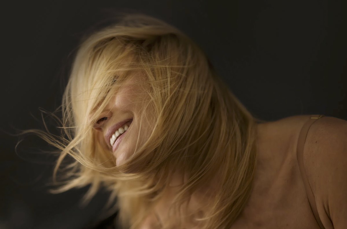 Blonde Frau lacht mit schwingendem Haar im warmen Licht — Das Studiozwei, Werbefotograf München