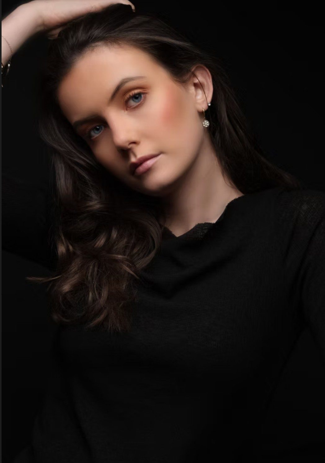 Junge Frau mit gewelltem Haar in schwarzem Oberteil im Low-Key-Beautyportrait — Das Studiozwei, Werbefotograf München