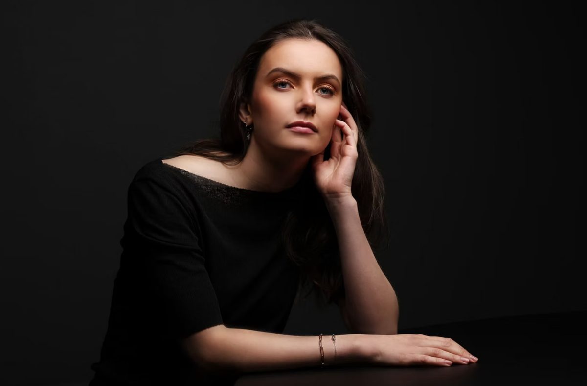 Dunkelhaarige Frau stuetzt den Kopf auf und blickt in die Kamera, Low-Key-Studioportrait — Das Studiozwei, Werbefotograf München