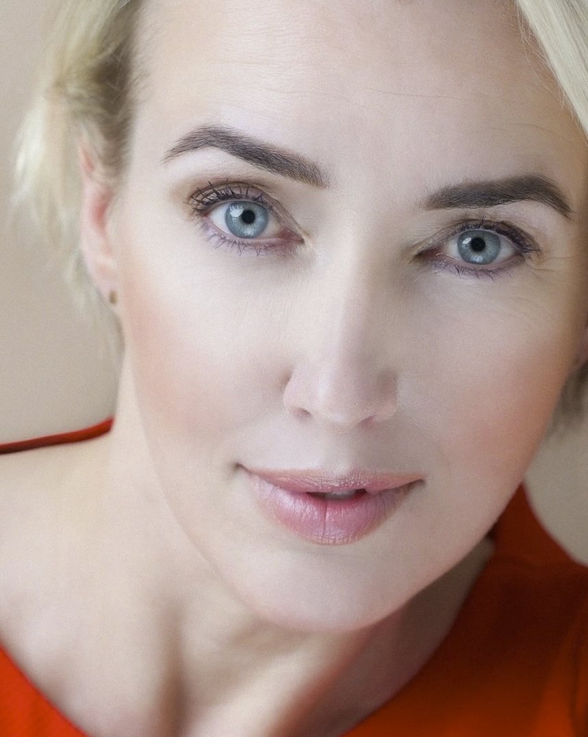 Nahes Beautyportrait einer blonden Frau mit blauen Augen in orangefarbenem Top — Das Studiozwei, Werbefotograf München