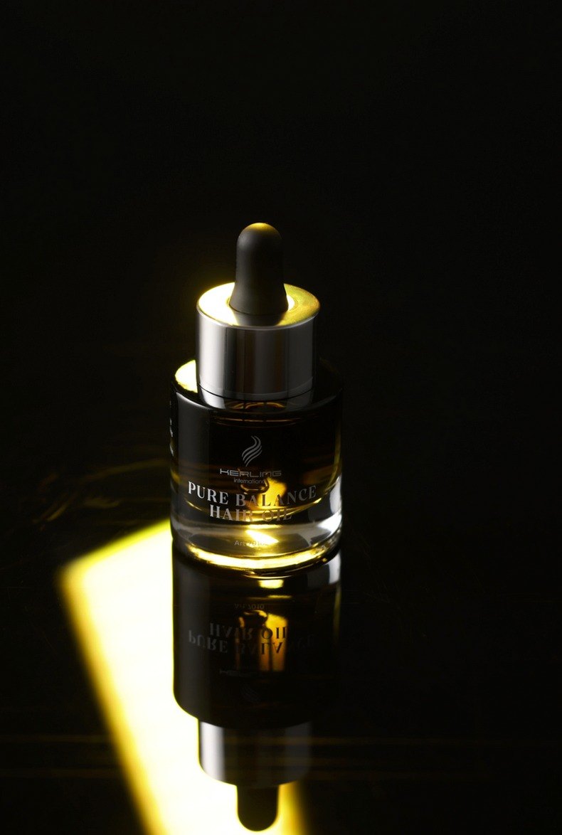 Dunkle Pure Balance Hair Oil Pipettenflasche in einem schmalen goldgelben Lichtstreifen vor schwarzem Hintergrund — Das Studiozwei, Werbefotograf München
