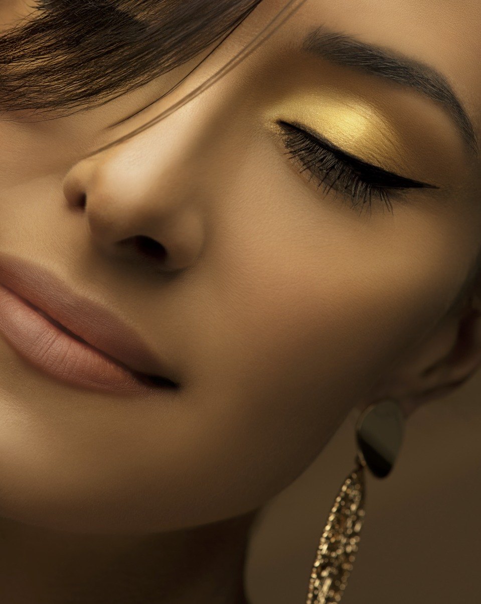 Beauty-Nahaufnahme eines Gesichts mit goldenem Lidschatten, schwarzem Eyeliner und glitzerndem Ohrgehaenge — Das Studiozwei, Werbefotograf München