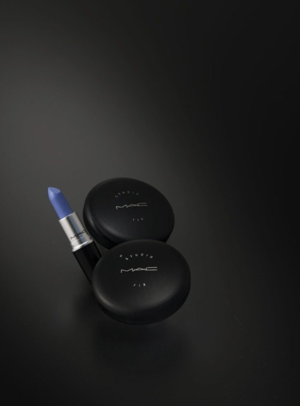Blauer MAC Lippenstift und zwei schwarze MAC Studio Fix Puderdosen auf dunkler Flaeche — Das Studiozwei, Werbefotograf München