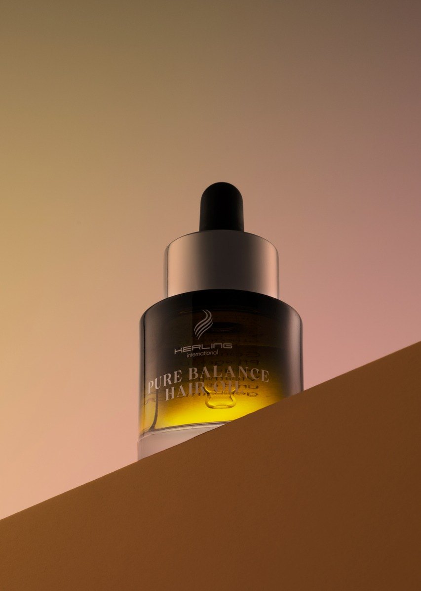 Kerling Pure Balance Hair Oil Flasche auf einer Kante vor pastelligem Rosa-Beige-Verlauf von unten fotografiert — Das Studiozwei, Werbefotograf München