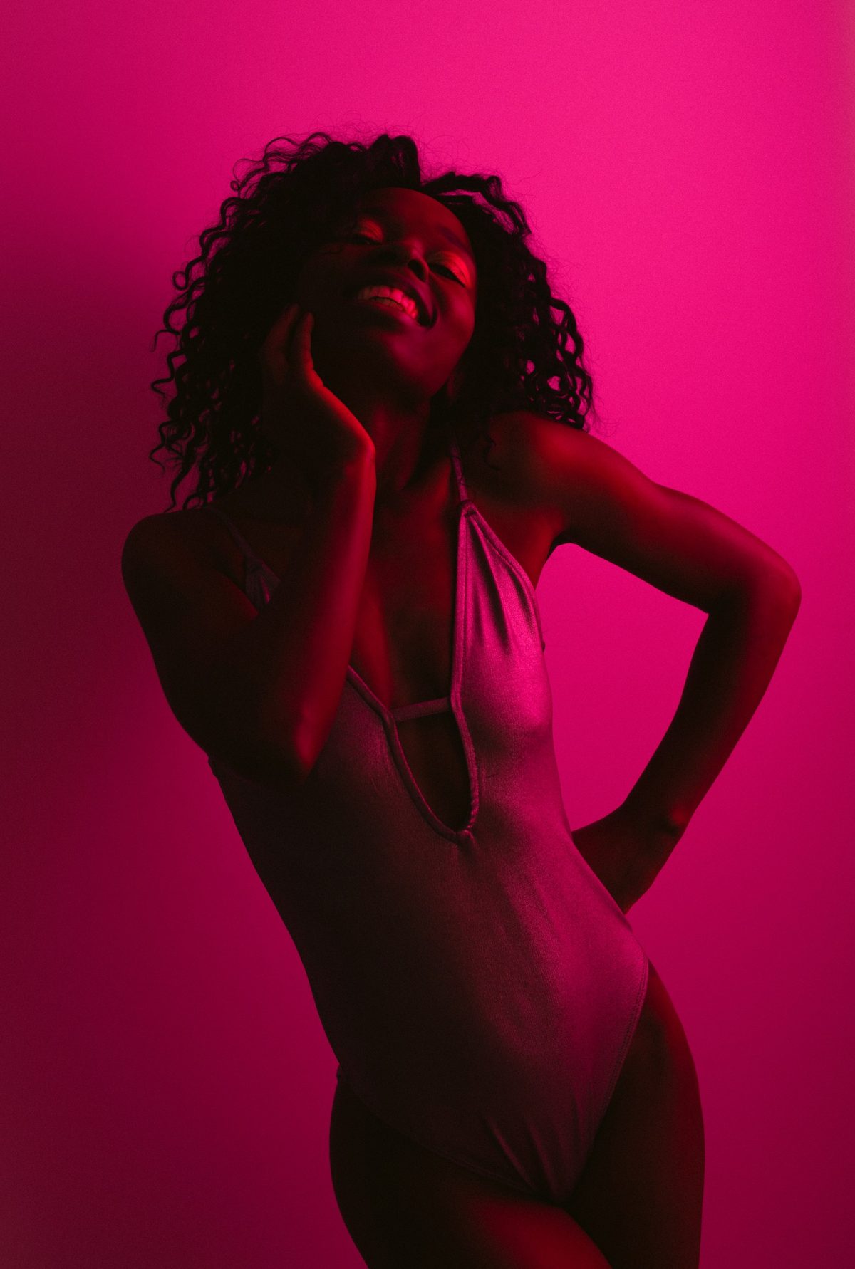 Lachendes Model im Bodysuit vor pinkfarbenem Studiohintergrund in monochromem Farblicht — Das Studiozwei, Werbefotograf München