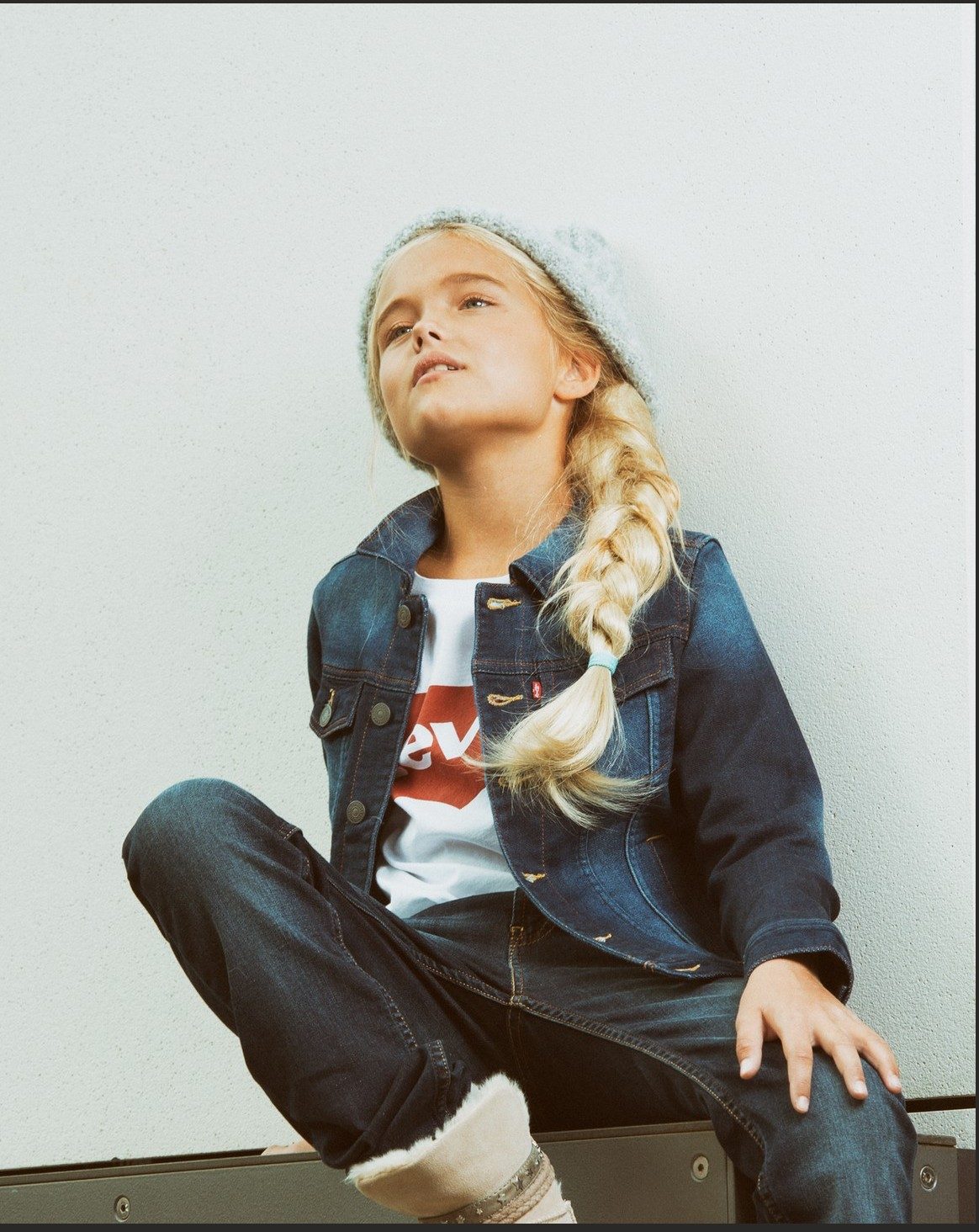 Sitzendes Maedchen mit Strickmuetze und Jeansjacke vor heller Wand — Das Studiozwei, Werbefotograf München