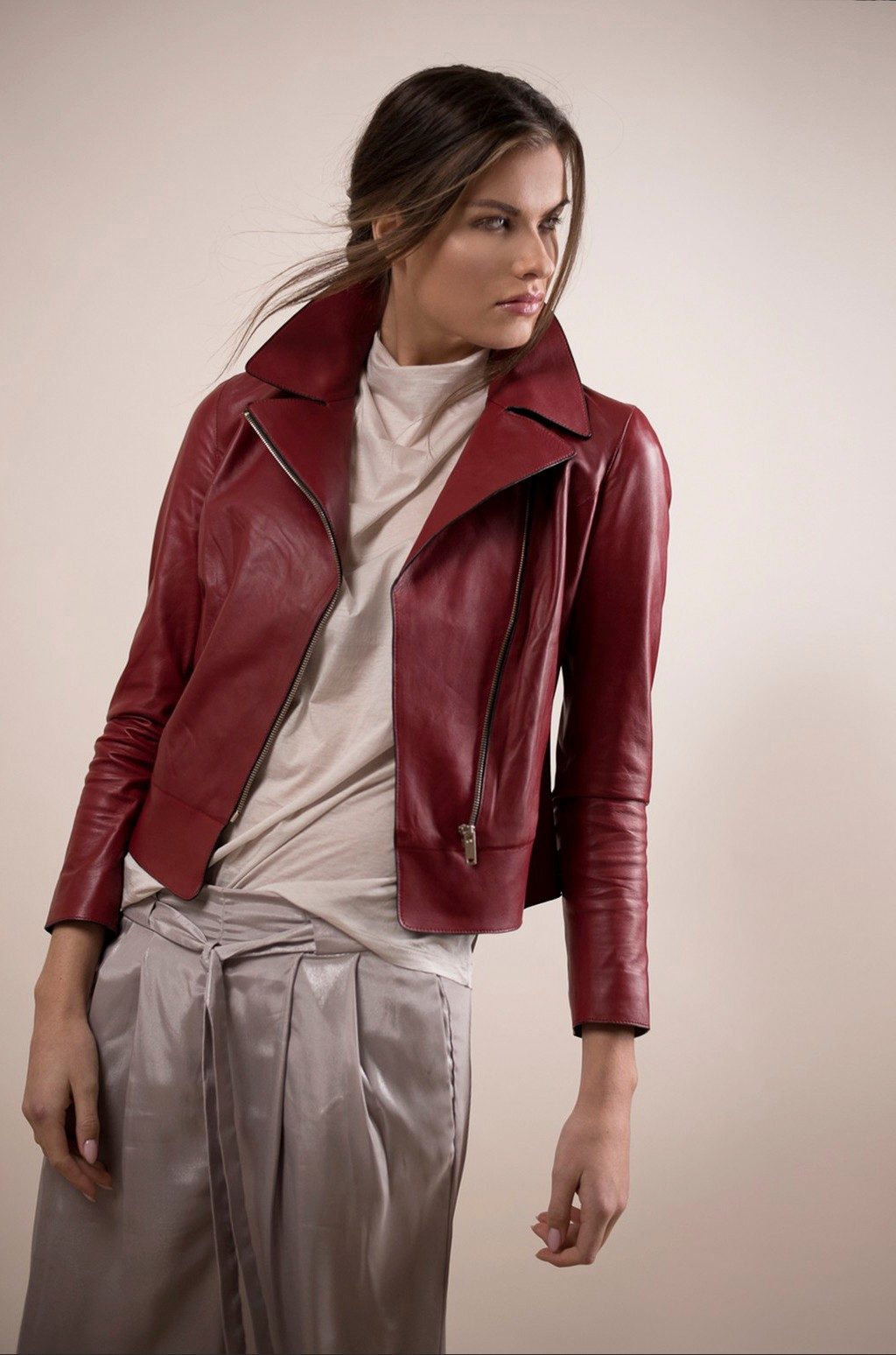 Model in dunkelroter Lederjacke und glaenzender Hose vor beigem Studiohintergrund — Das Studiozwei, Werbefotograf München
