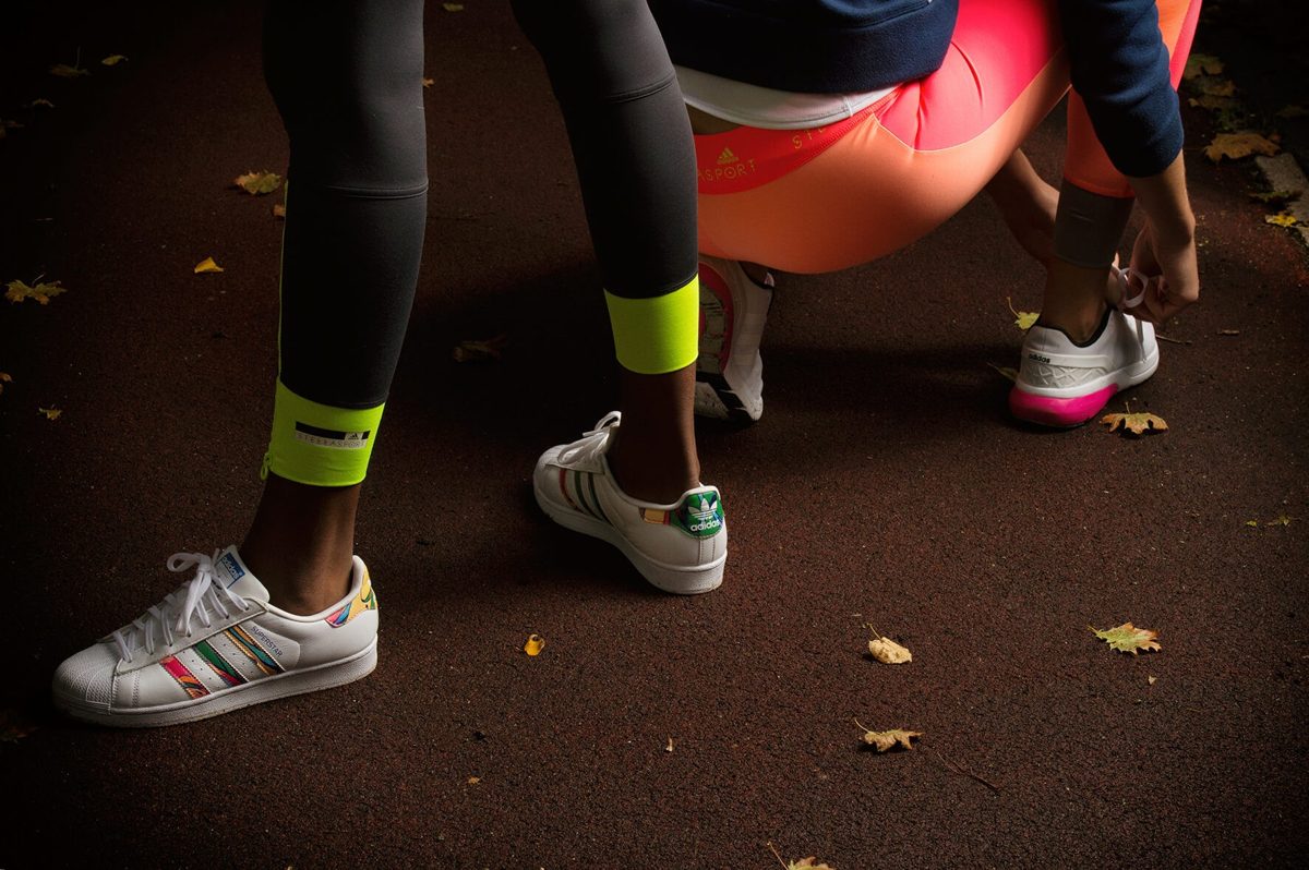 Detailaufnahme weisser Sneaker und Sportleggings auf herbstlichem Asphalt — Das Studiozwei, Werbefotograf München