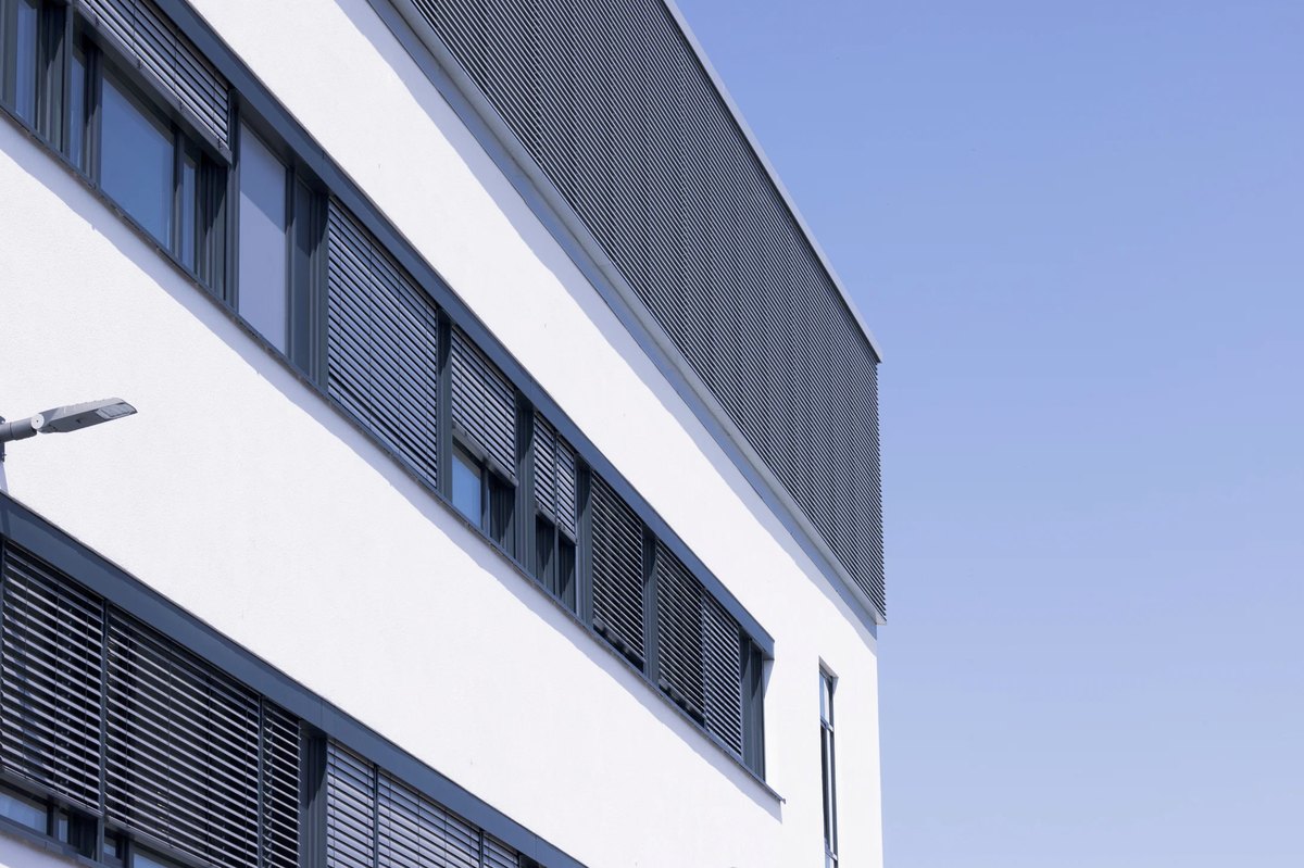 Moderne Buerofassade mit umlaufendem Fensterband und weisser Attika — Das Studiozwei, Werbefotograf München