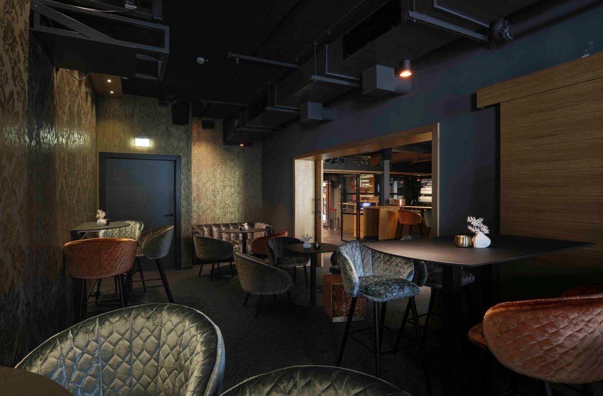 Dunkle Lounge mit Samtsesseln in Petrol und Orange und beleuchteter Bar im Hintergrund — Das Studiozwei, Werbefotograf München