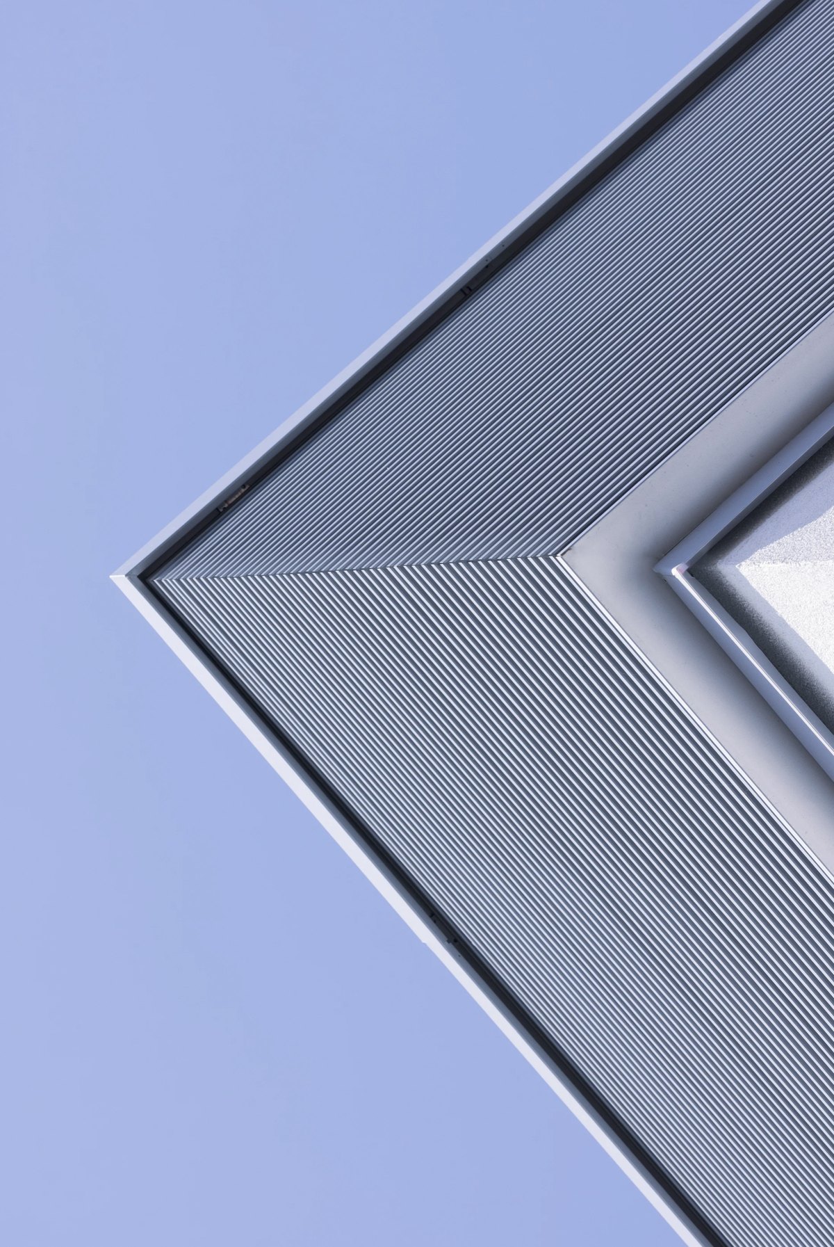 Grafische Gebaeudeecke mit feiner Lamellenfassade vor hellblauem Himmel — Das Studiozwei, Werbefotograf München