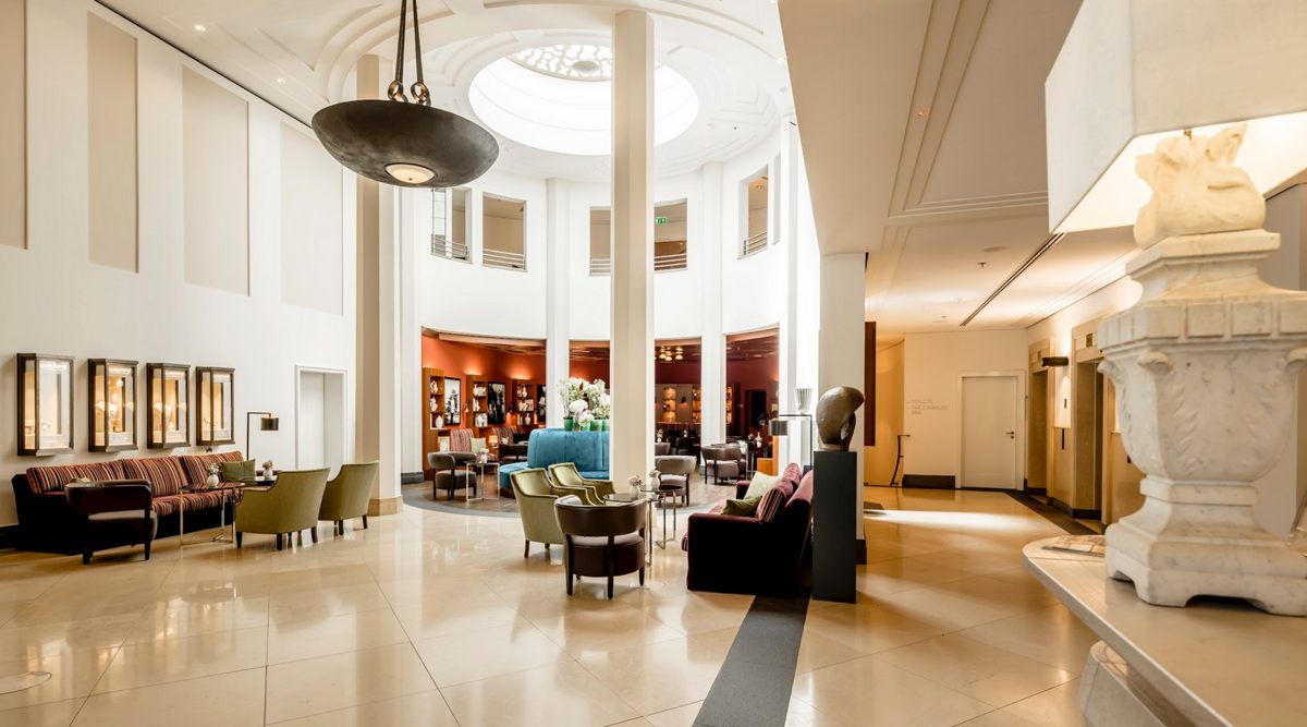 Helle Hotellobby mit weissen Saeulen, Oberlicht und farbigen Sitzgruppen — Das Studiozwei, Werbefotograf München