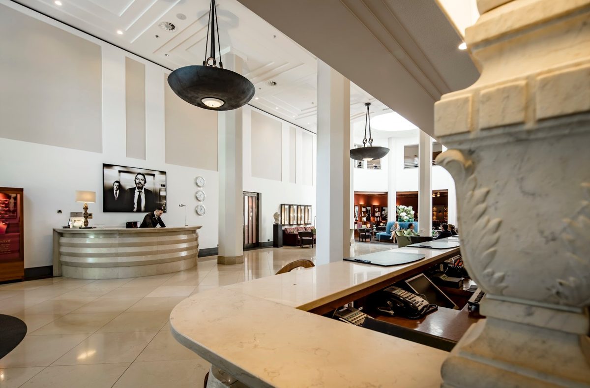 Empfangsbereich mit geschwungener Rezeptionstheke und Pendelleuchten in heller Lobby — Das Studiozwei, Werbefotograf München