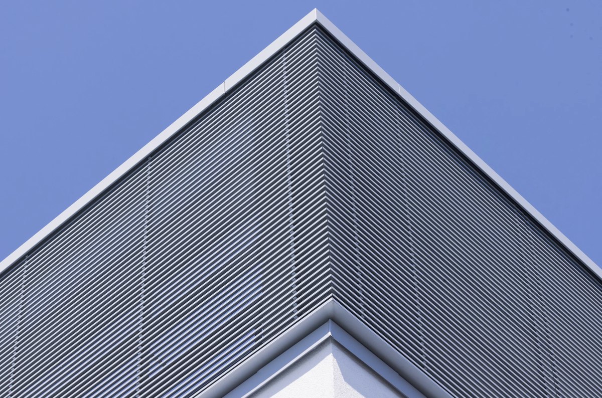 Giebel eines Neubaus mit horizontaler Lamellenfassade vor blauem Himmel — Das Studiozwei, Werbefotograf München