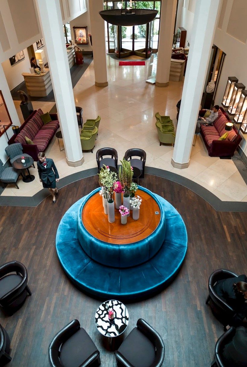 Hotellobby von oben mit runder tuerkisfarbener Sitzbank und Blumenarrangement — Das Studiozwei, Werbefotograf München
