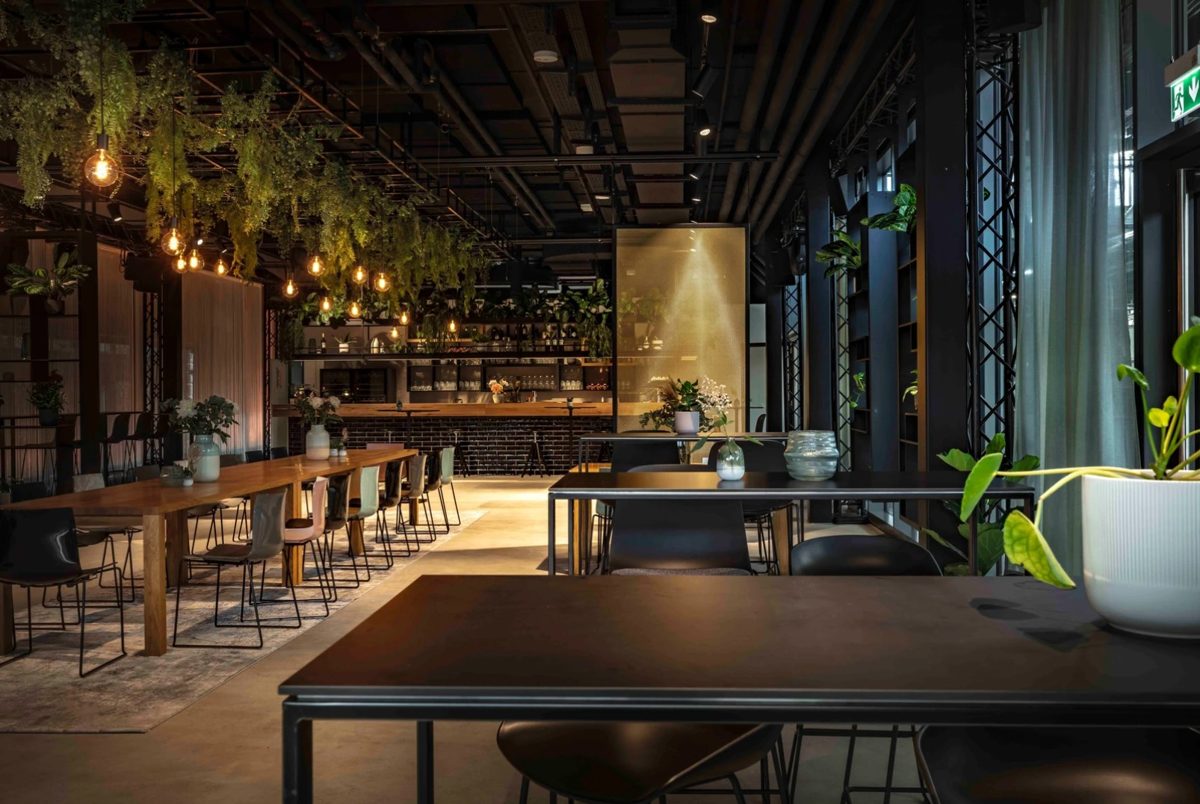 Loftartiges Restaurant mit haengenden Pflanzen, Gluehbirnen und warm beleuchteter Bar — Das Studiozwei, Werbefotograf München