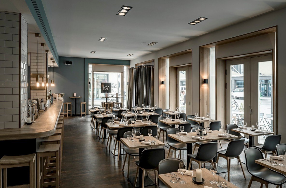 Heller Restaurantraum mit Bartheke, Holztischen und schwarzen Stuehlen im Tageslicht — Das Studiozwei, Werbefotograf München