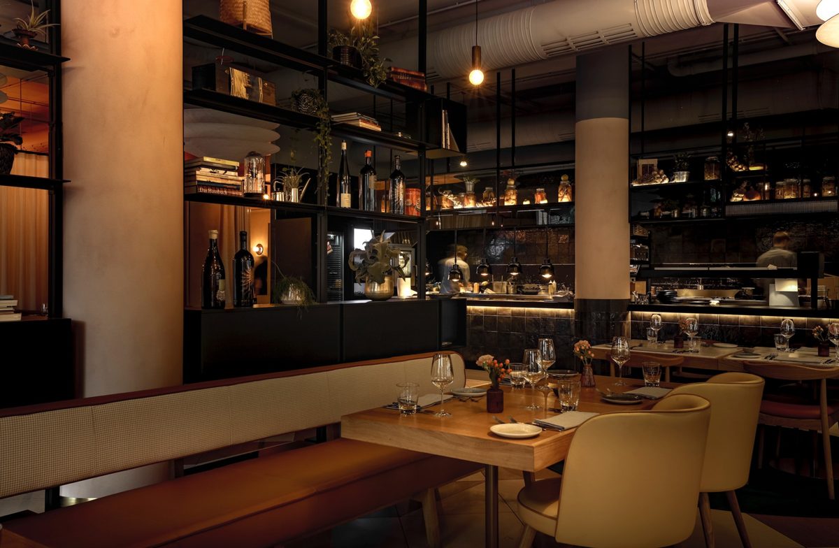 Restaurantnische mit Sitzbank, gelben Stuehlen und Regalsystem vor offener Kueche — Das Studiozwei, Werbefotograf München