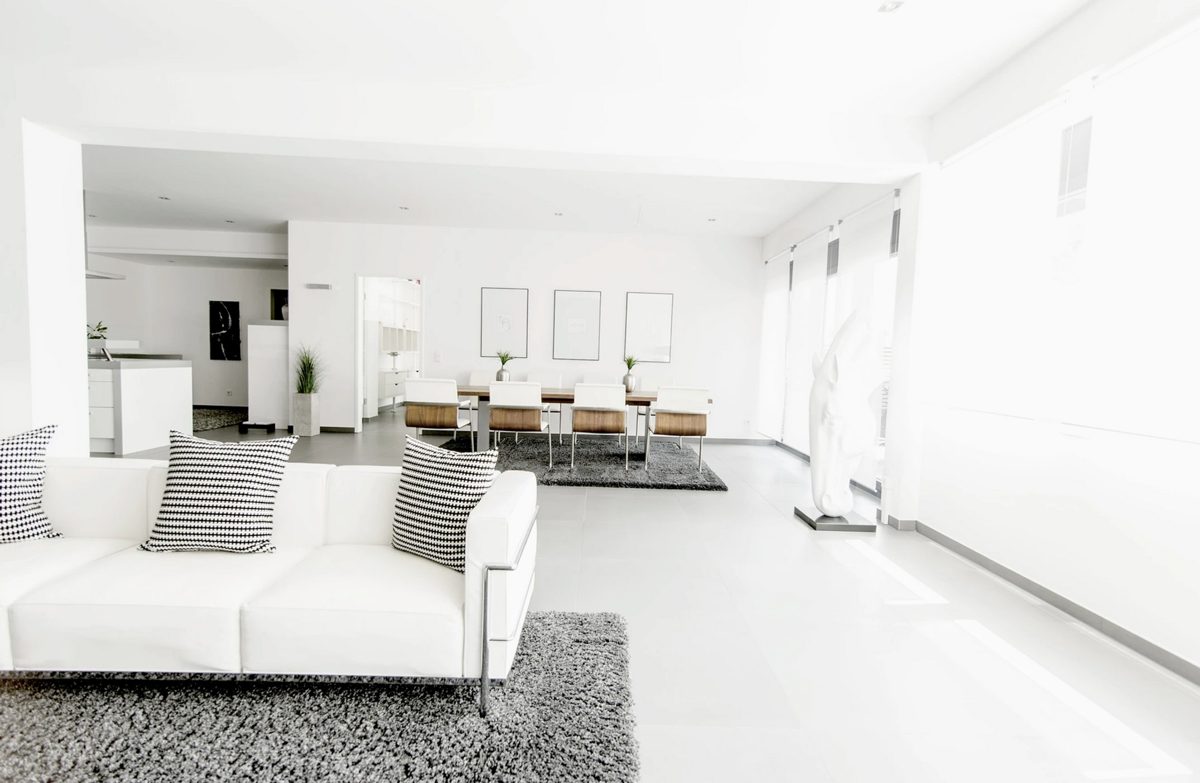 Offener heller Wohn- und Essbereich mit weisser Ledercouch und grauen Teppichen — Das Studiozwei, Werbefotograf München