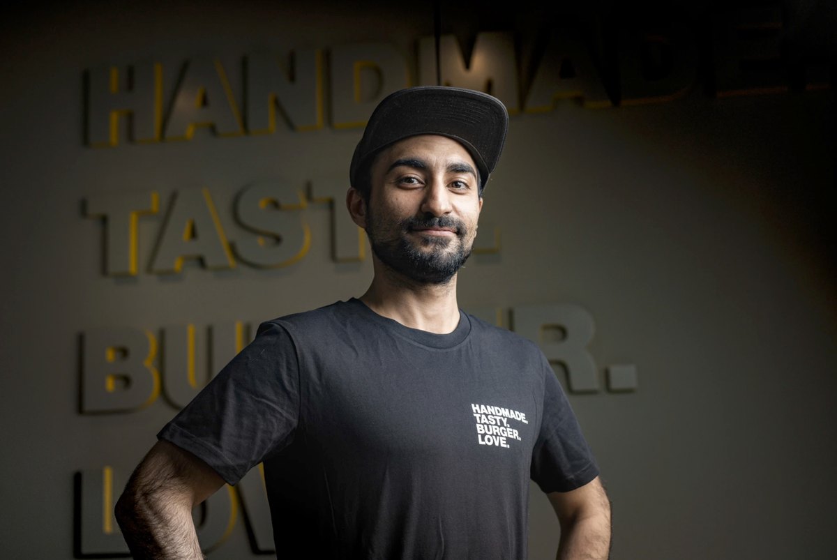 Barista im Portrait vor beleuchtetem Schriftzug an der Wand — Das Studiozwei, Werbefotograf München