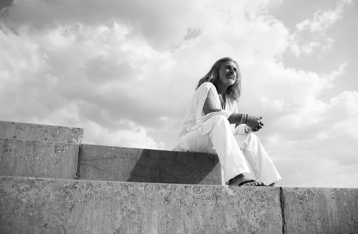 Frau in weisser Kleidung sitzt auf einer Betonmauer vor grossem Wolkenhimmel in Schwarzweiss — Das Studiozwei, Werbefotograf München