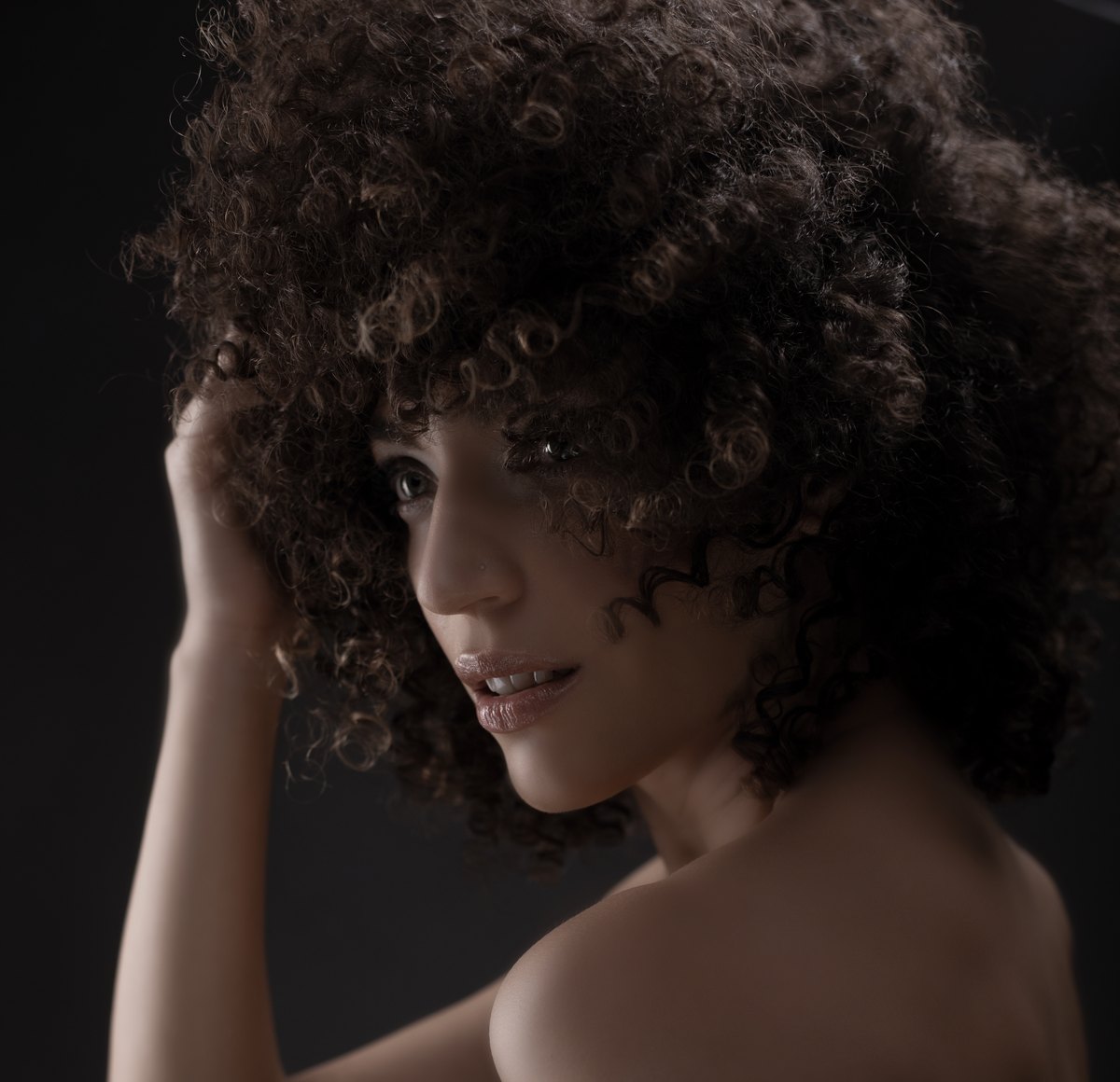 Frau mit voluminoesen Afrolocken im Schulterblick — Das Studiozwei, Werbefotograf München