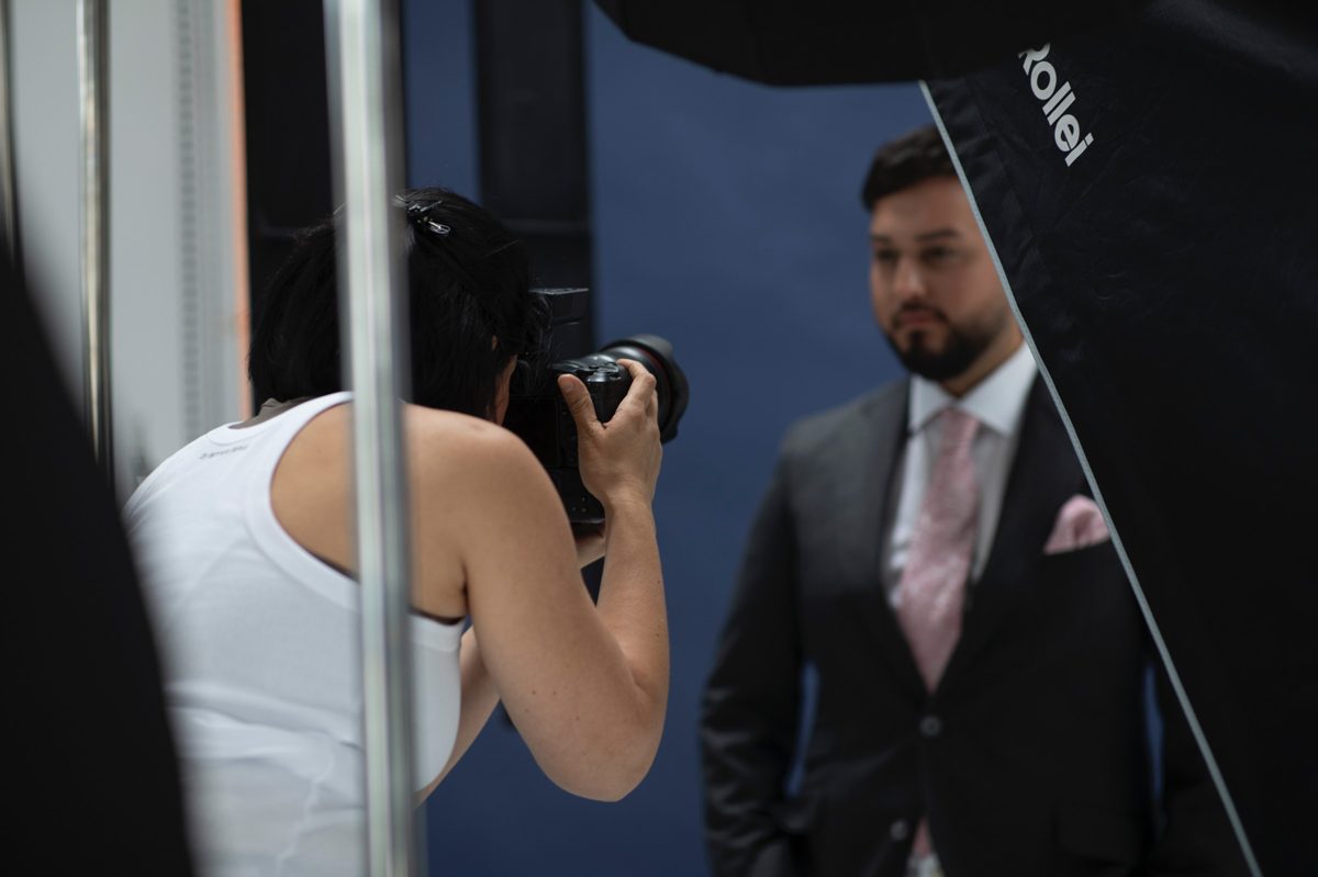 Fotografin beim Business-Portraetshooting eines Mannes im Anzug vor blauem Hintergrund — Das Studiozwei, Werbefotograf München