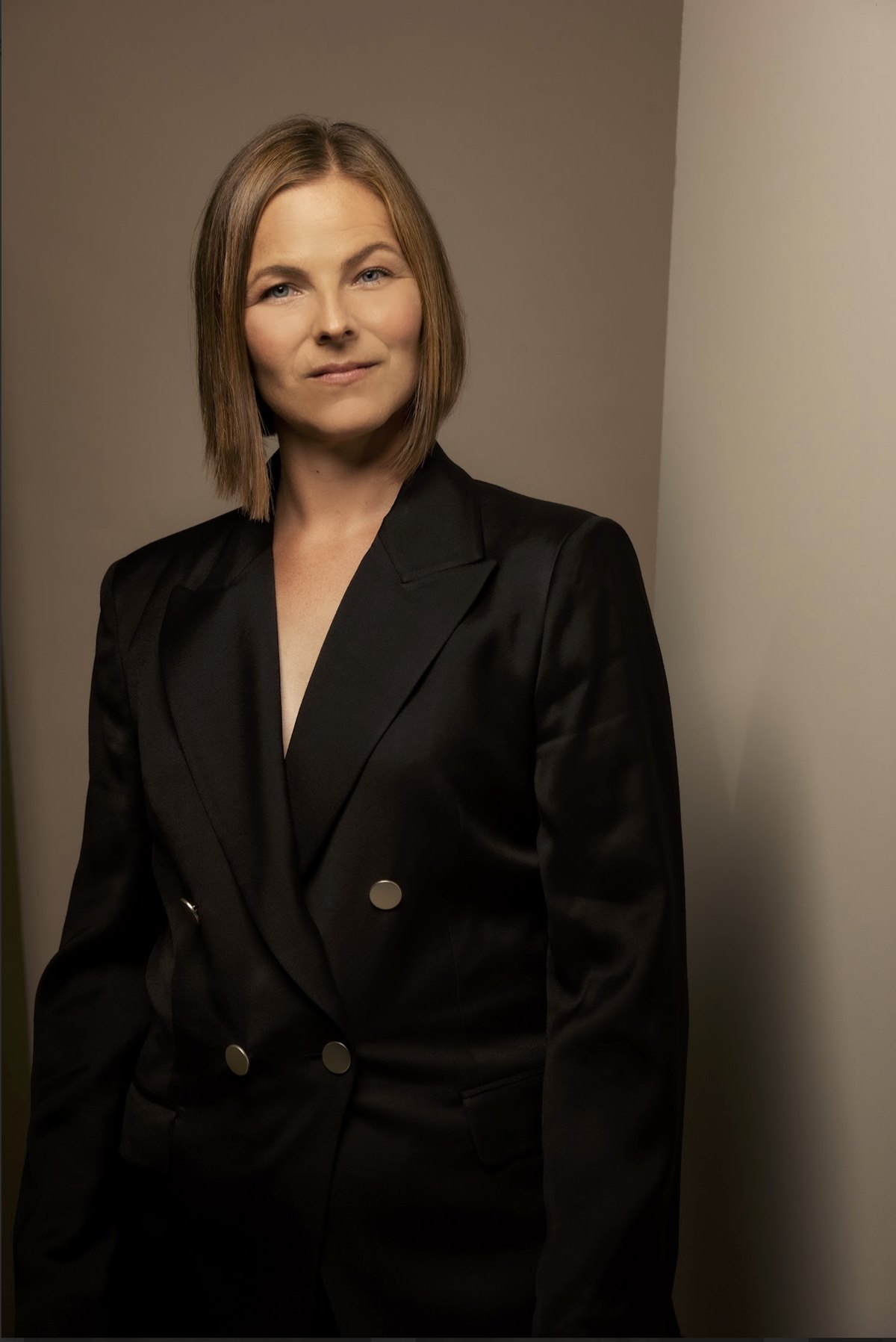 Portrait einer Frau im schwarzen Blazer vor warm beleuchteter Wand — Das Studiozwei, Werbefotograf München