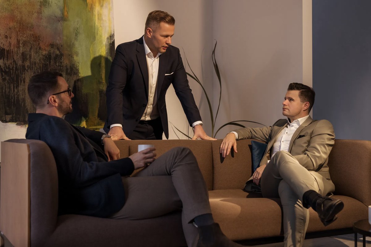 Drei Maenner im Gespraech in einer hellen Lounge — Das Studiozwei, Werbefotograf München