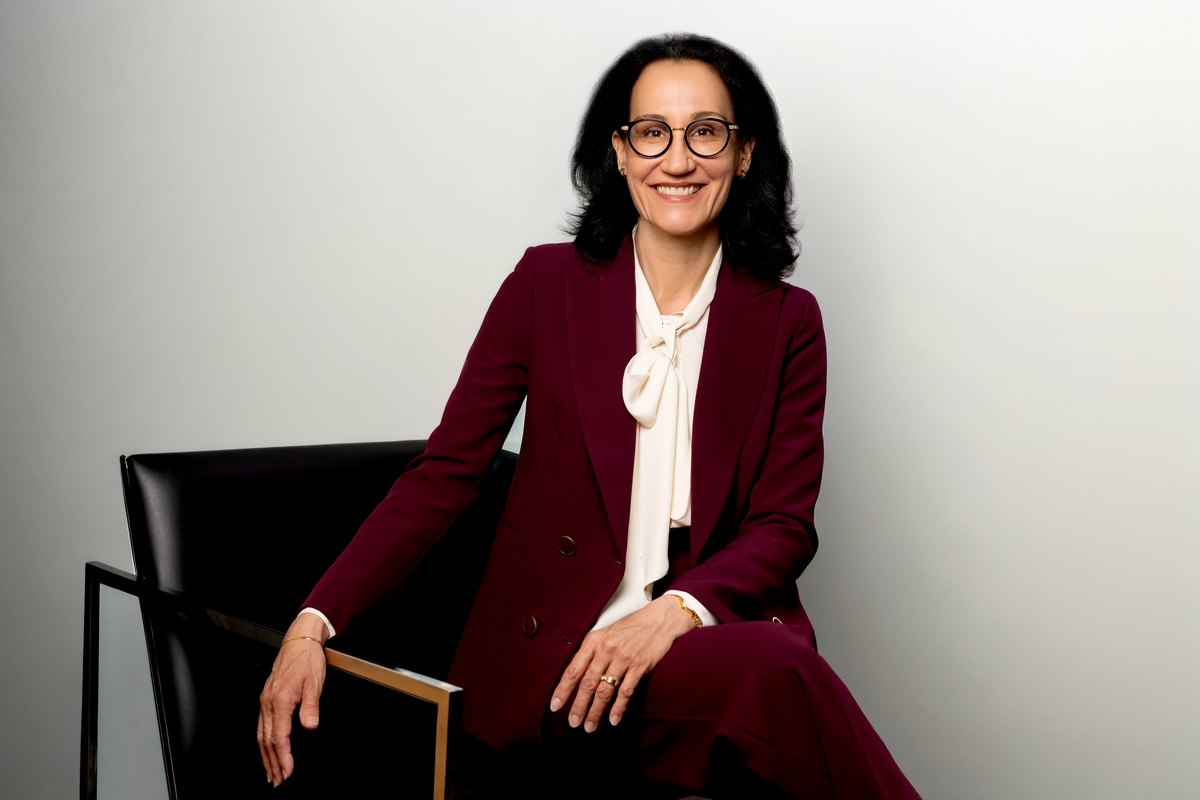 Frau im bordeauxroten Anzug mit Brille auf einem Designstuhl — Das Studiozwei, Werbefotograf München