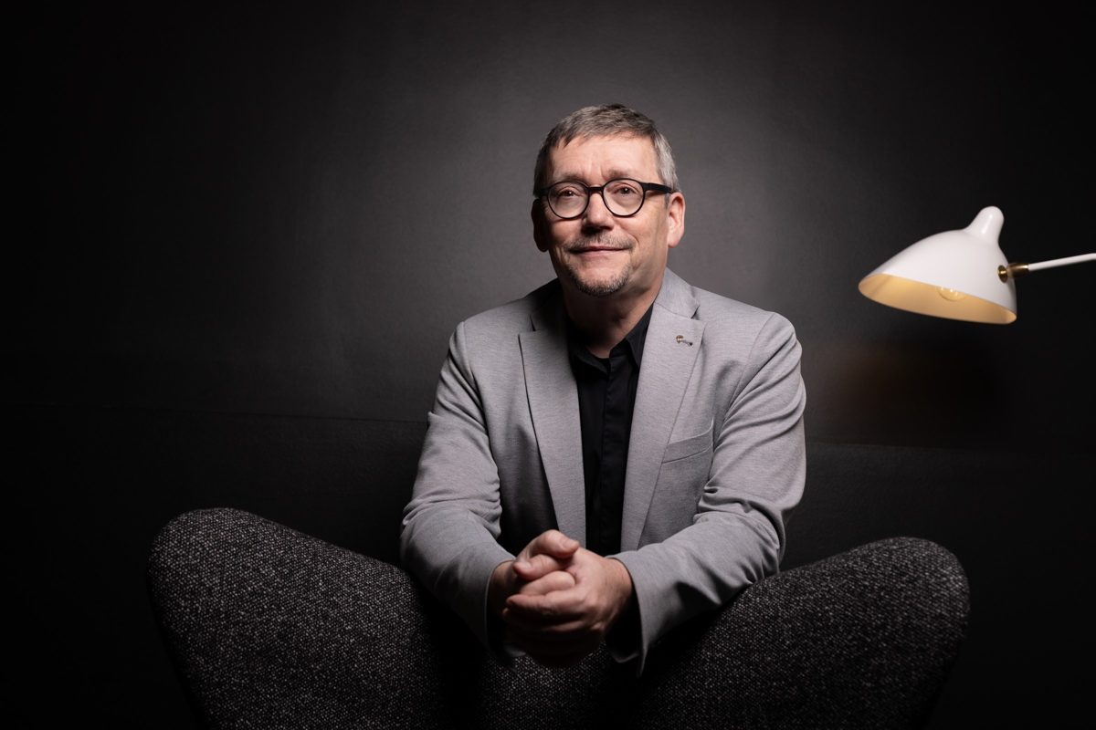 Businessportrait eines Mannes mit Brille im grauen Sakko vor dunklem Studiohintergrund — Das Studiozwei, Werbefotograf München