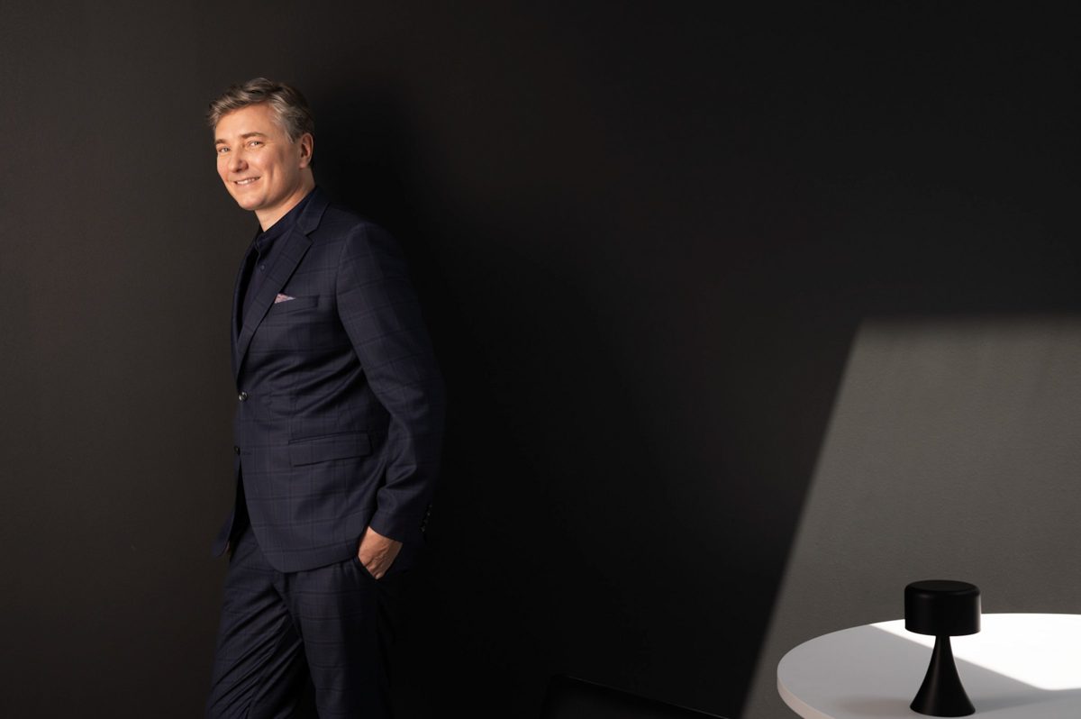 Businessportrait eines Mannes im dunkelblauen Anzug an einer dunklen Wand mit hellem Lichtfeld — Das Studiozwei, Werbefotograf München