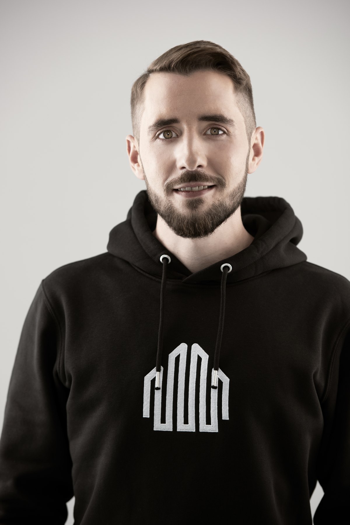 Portrait eines Mitarbeiters im schwarzen Hoodie mit Firmenlogo — Das Studiozwei, Werbefotograf München