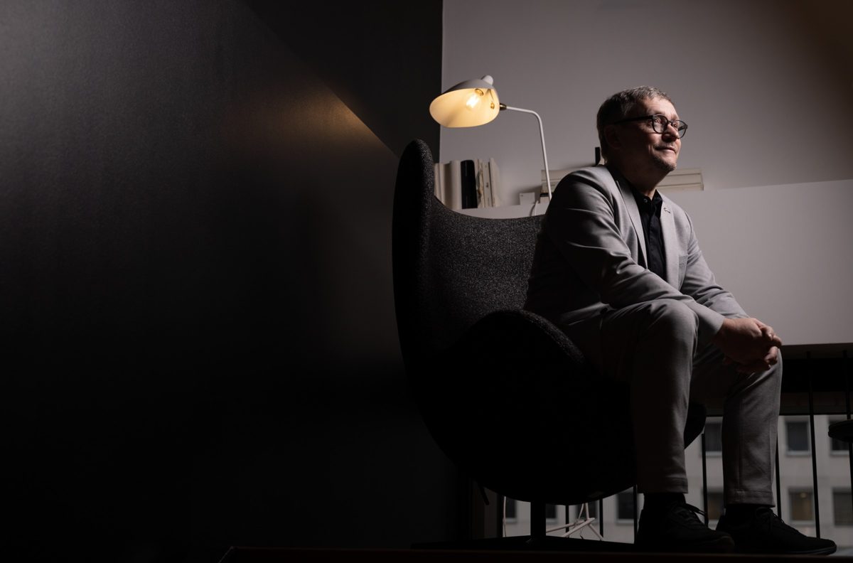 Mann im Anzug sitzt in dunkler Raumstimmung neben einer leuchtenden Stehlampe im Sessel — Das Studiozwei, Werbefotograf München