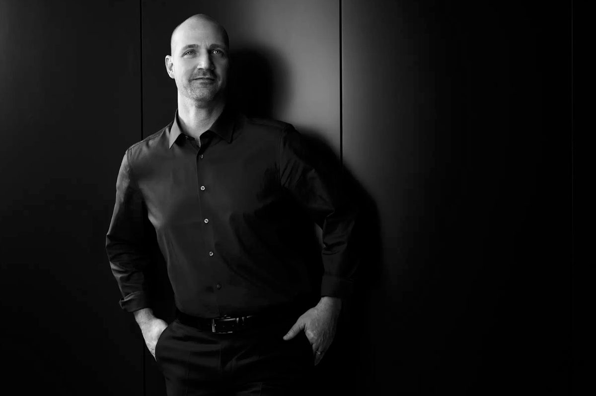 Stehendes Schwarzweiss-Businessportrait eines Mannes vor dunkler Wand mit Schattenwurf — Das Studiozwei, Werbefotograf München