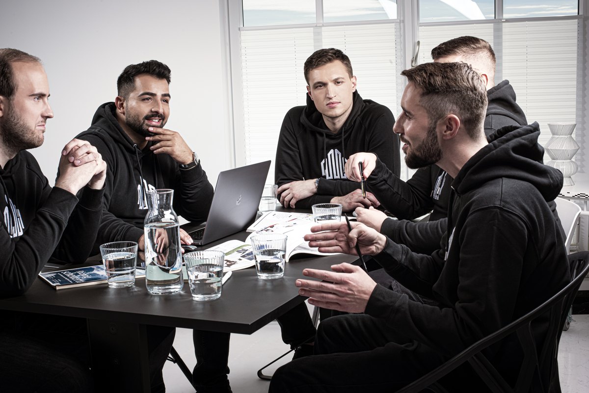 Team in dunkler Arbeitskleidung bei einer Besprechung am Laptop — Das Studiozwei, Werbefotograf München