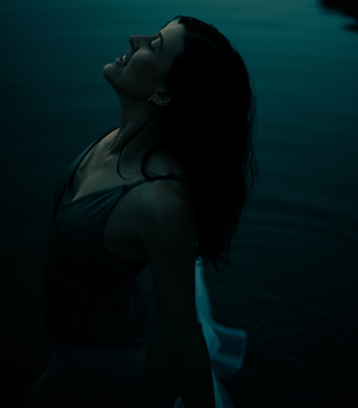Frau im Wasser mit zurueckgelegtem Kopf in tuerkiser Lichtstimmung — Das Studiozwei, Werbefotograf München