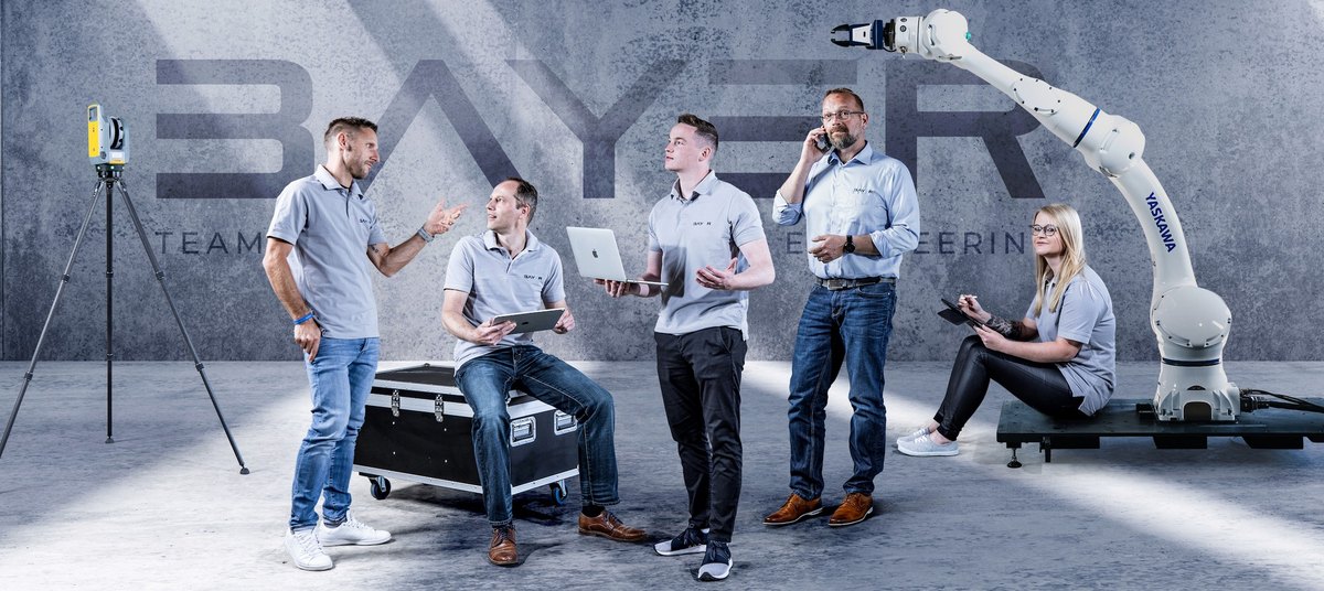 Fuenfkoepfiges Team gruppiert um Industrieroboterarm und Messtechnik — Das Studiozwei, Werbefotograf München