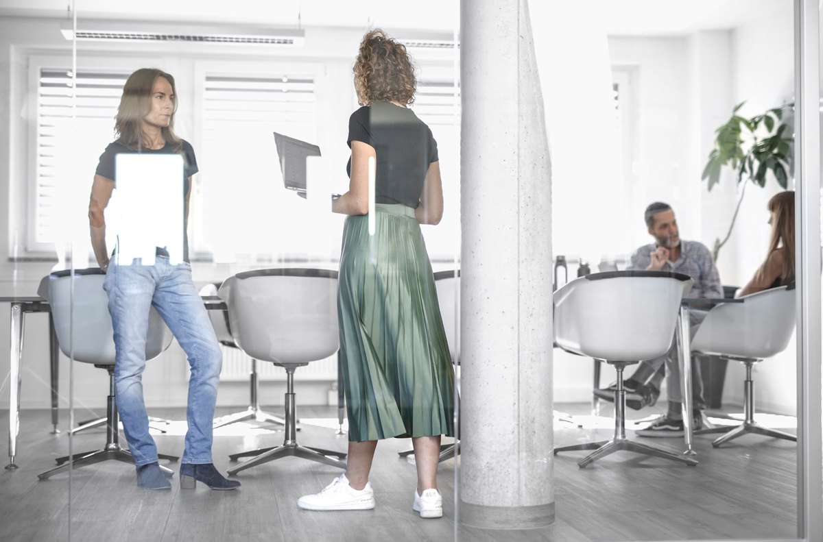 Personen im Gespraech vor Glaswand im modernen Buero — Das Studiozwei, Werbefotograf München