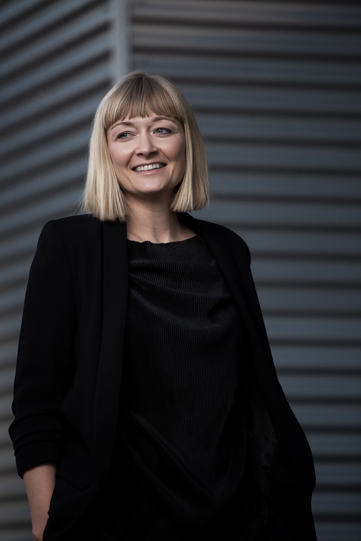 Ganzkoerperportrait einer Frau in Schwarz vor Metallfassade — Das Studiozwei, Werbefotograf München
