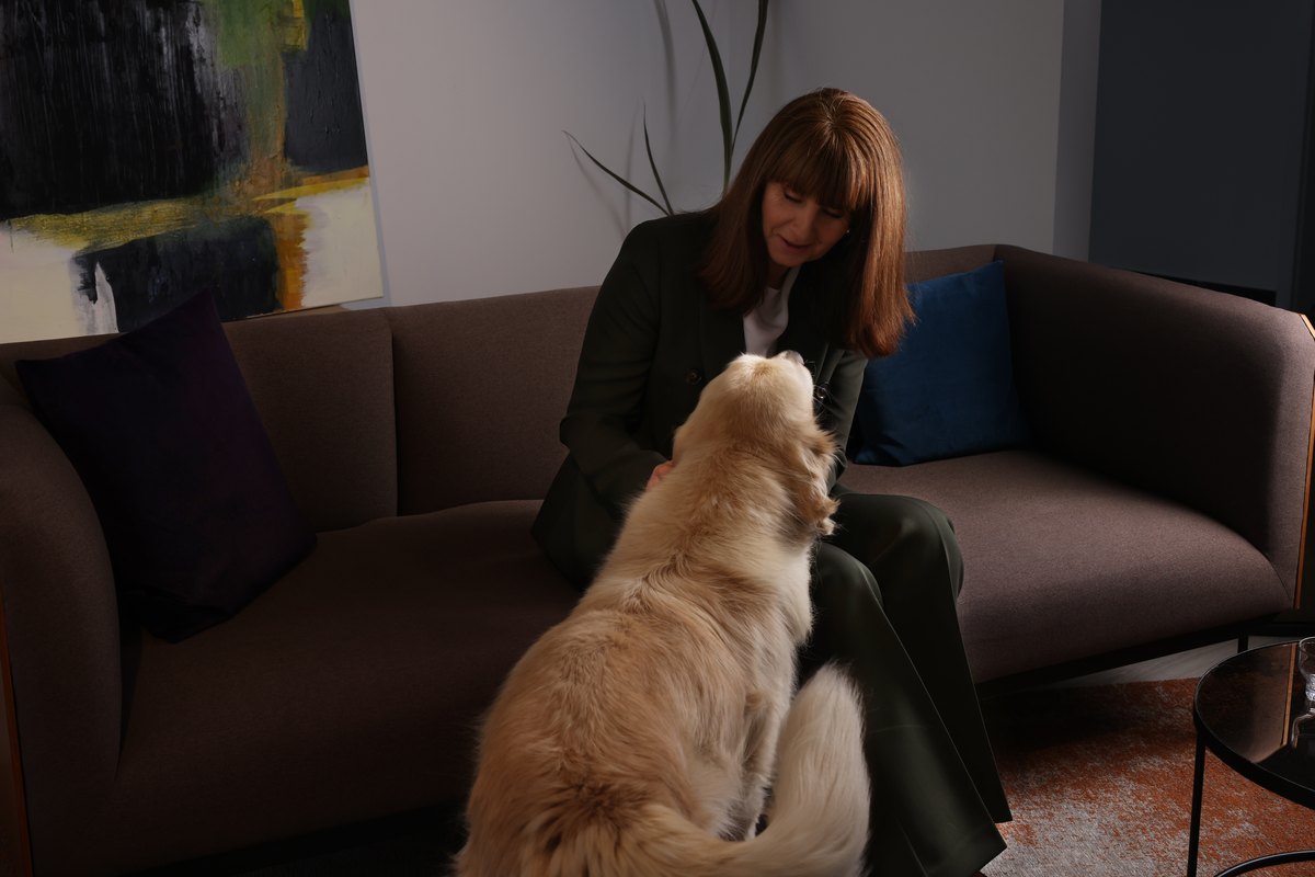 Frau sitzt mit ihrem Hund auf einem Sofa im hellen Wohnraum — Das Studiozwei, Werbefotograf München