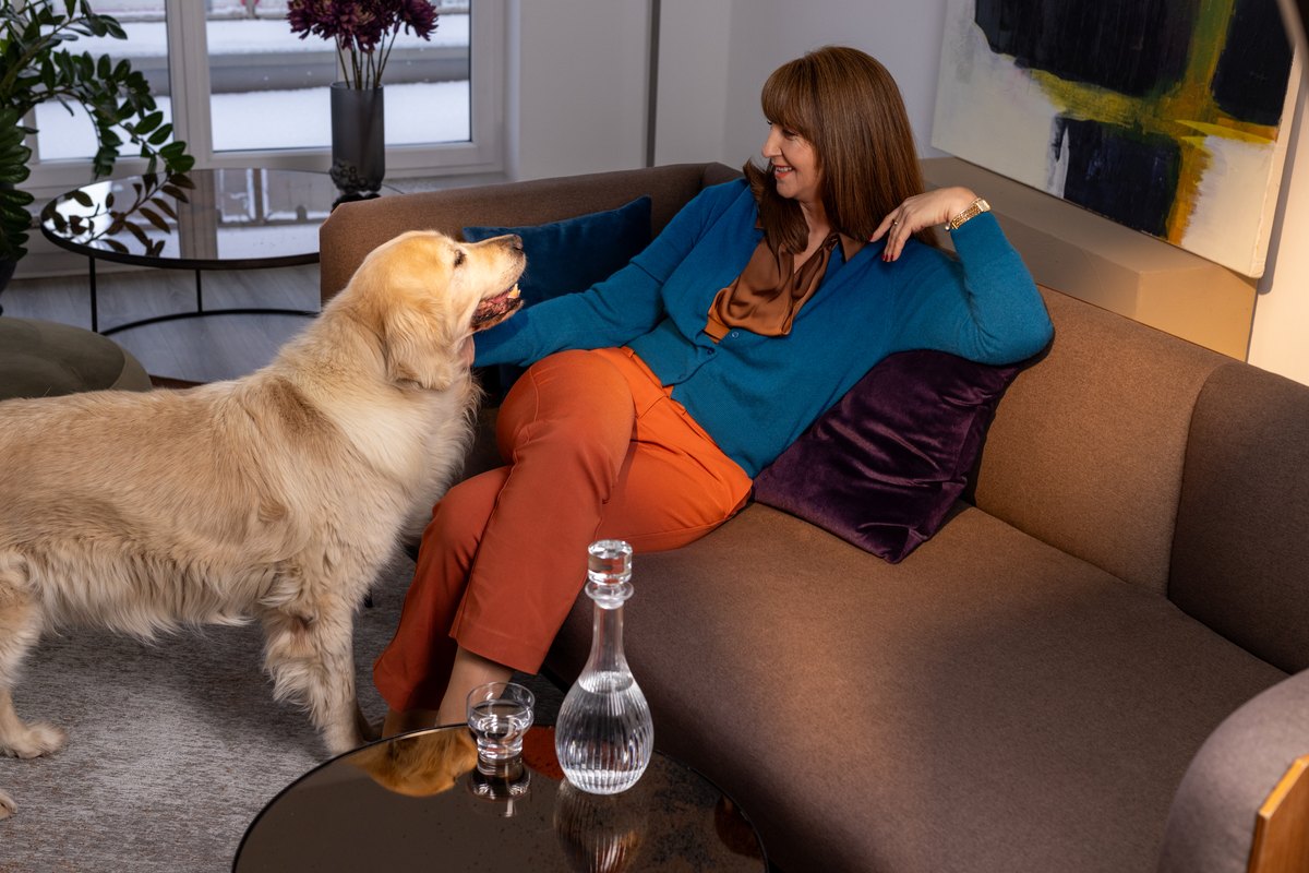 Frau in Blau und Orange liegt mit Hund auf dem Sofa im hellen Raum — Das Studiozwei, Werbefotograf München