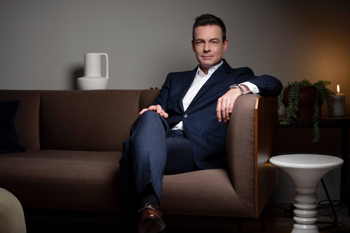 Mann im dunklen Anzug sitzt auf einem Sofa in dunkler Lounge — Das Studiozwei, Werbefotograf München