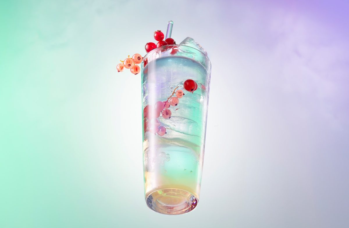 Schwebender Becher mit schimmerndem Drink, Eis und Johannisbeeren vor mint-fliederfarbenem Verlauf — Das Studiozwei, Werbefotograf München