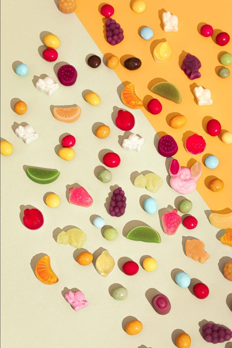 Bunte Frucht- und Geleebonbons im Raster auf gruen-orangem Hintergrund von oben fotografiert — Das Studiozwei, Werbefotograf München