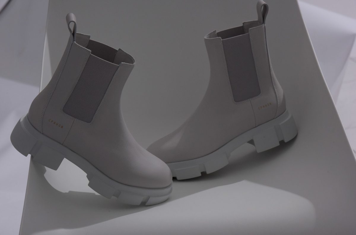 Zwei helle Chelsea Boots auf gefaltetem weissem Papier im weichen Studiolicht — Das Studiozwei, Werbefotograf München
