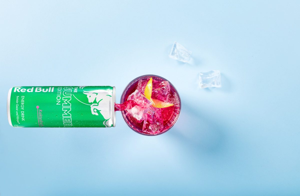 Gruene Getraenkedose und Glas mit pinkem Drink von oben auf hellblauem Hintergrund — Das Studiozwei, Werbefotograf München