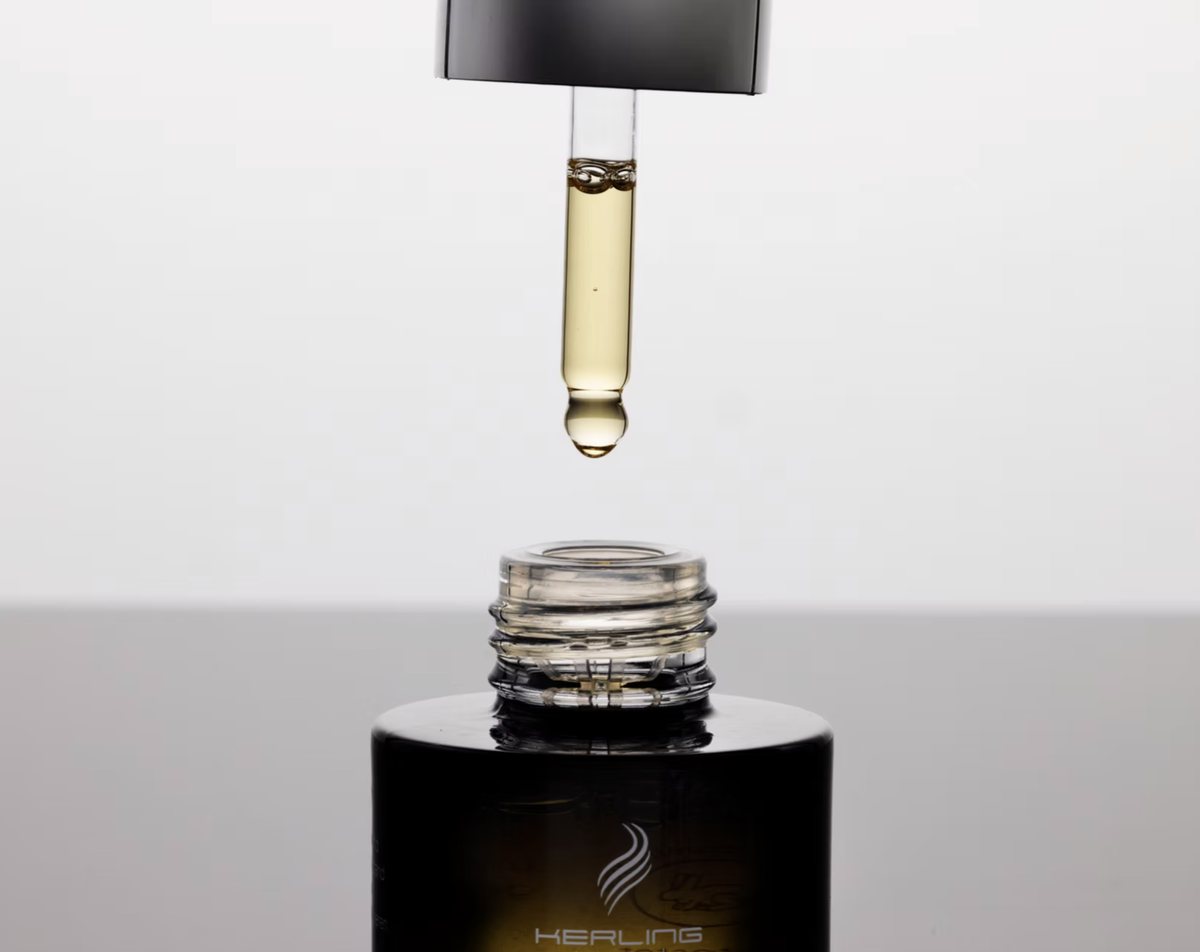 Pipette mit goldenem Haaroel ueber geoeffneter Flasche, Studioaufnahme — Das Studiozwei, Werbefotograf München