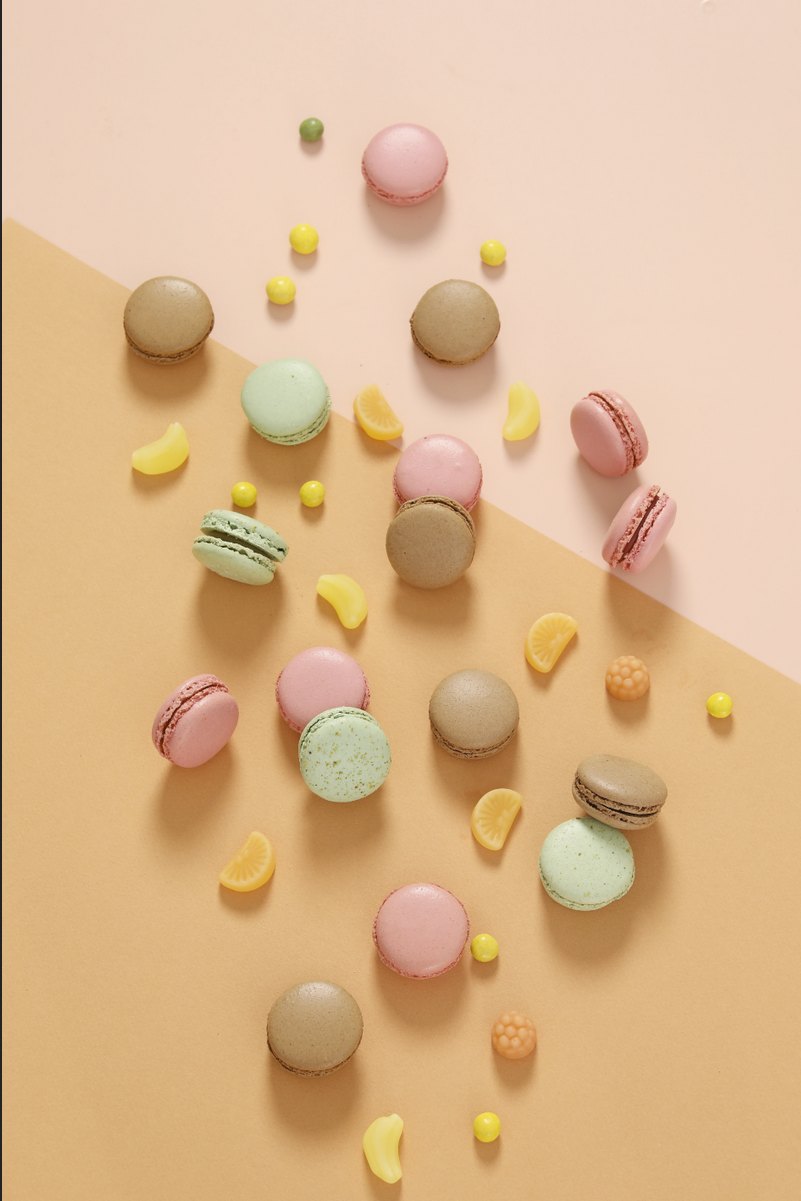 Macarons und Bonbons verstreut auf pastellfarbenem Hintergrund — Das Studiozwei, Werbefotograf München